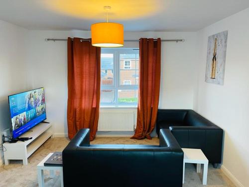 a living room with a couch and a tv and a window at Anox serviced Apartments 2 in Newcastle upon Tyne
