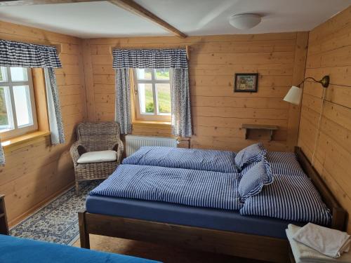a bedroom with two beds and a chair and windows at Penzion Bouda Na stráni in Dolní Malá Úpa