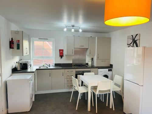 a kitchen with a white table and white chairs at Anox serviced Apartments 2 in Newcastle upon Tyne