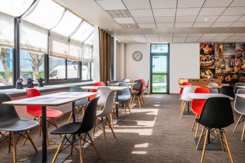 a dining room with tables and chairs and windows at ibis Paris Creteil in Cr&eacute;teil