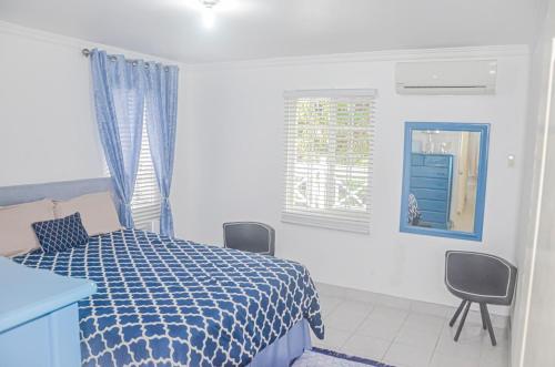 a bedroom with a blue and white bed and chairs at Bamboo Vacation Home in Lewis