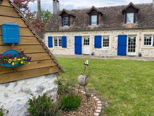 une maison avec des volets bleus et un oiseau dans une cour dans l'établissement Maison de Campagne Le Pâtis aux Chevaux proche circuit 24H et Le Mans, à Challes