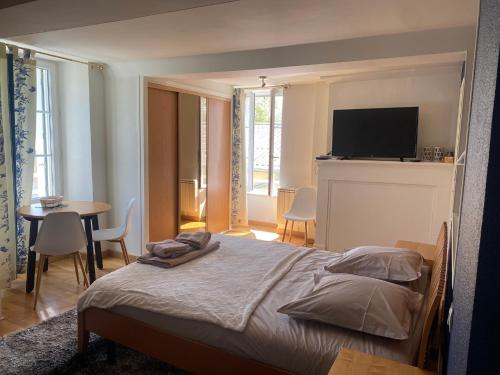 um quarto com uma cama, uma mesa e uma televisão em La Suite Le Nôtre em Colleville-sur-Mer