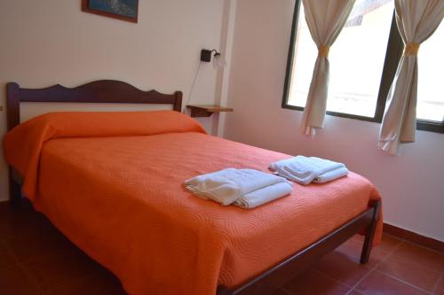 2 toallas en una cama con manta naranja en Complejo Playa Norte en Mar de Ajó
