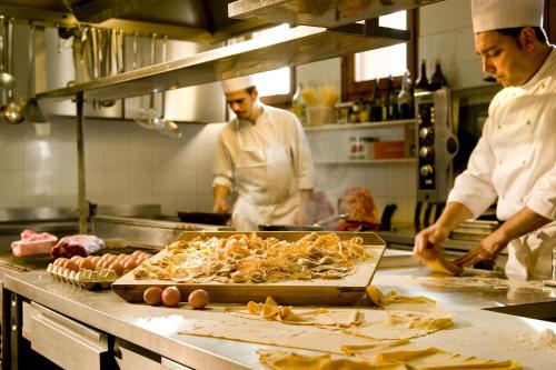 two men in a kitchen preparing food in a kitchen at Hotel Noce in Brescia