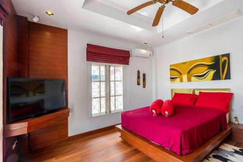 a bedroom with a bed with red pillows and a tv at Recommend a warm Thai style private swimming pool villa with convenient traffic and living, walking 700 meters to the the beach in Kamala Beach