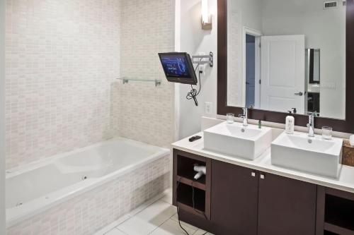 baño con 2 lavabos, bañera y TV en UPSCALE RESORT VILLA IN THE HEART OF MIAMI en Miami