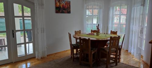 Un comedor con mesa y sillas y ventanas. en Casa Bănucu, en Satu Mare