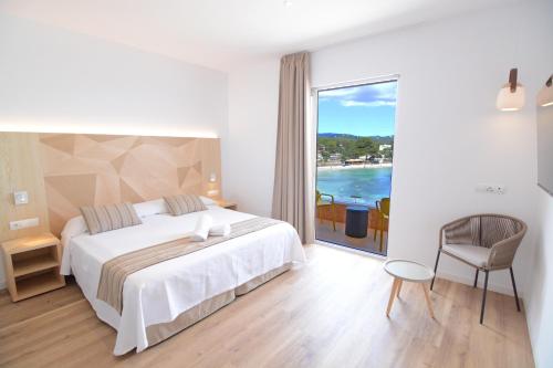 a bedroom with a bed and a view of the ocean at Apartamentos Playa Sol in Es Cana
