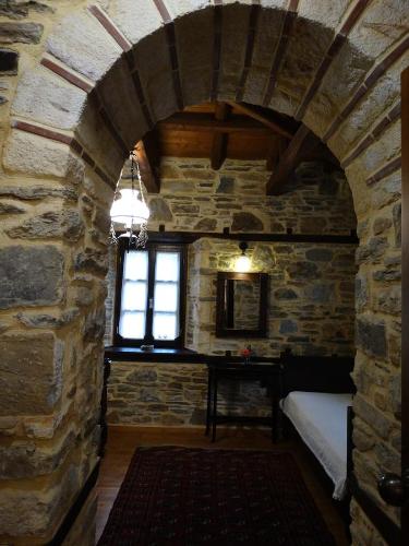 a room with a stone wall with a bed and a table at Iliopetra Suites in Agios Lavredios