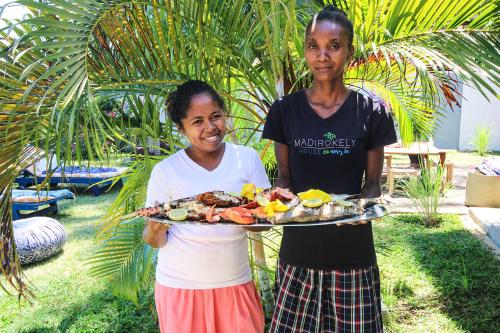 a man and a woman holding a tray of food at MADIROKELY HOUSE Nosy Be in Ambatoloaka