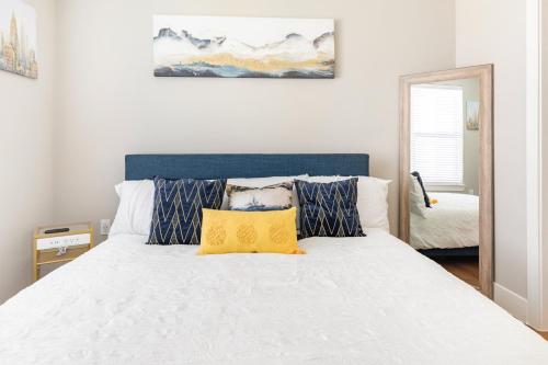 een slaapkamer met een wit bed en een geel kussen bij Elegant & Luxurious Modern Apartment with Southern Charm in Fort Worth
