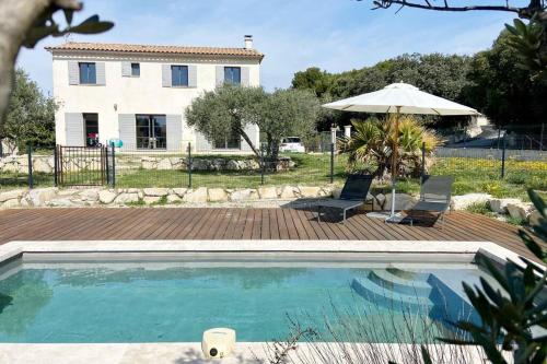 una piscina con sombrilla y una casa en Mas Provençale au calme Piscine, en Vacqueyras