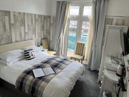 a bedroom with a bed and a desk and a window at Shellseekers Guest House in Looe