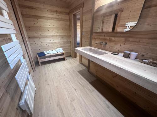 een badkamer met een wastafel en een houten muur bij Chalet La Petite Ourse in Hohrod