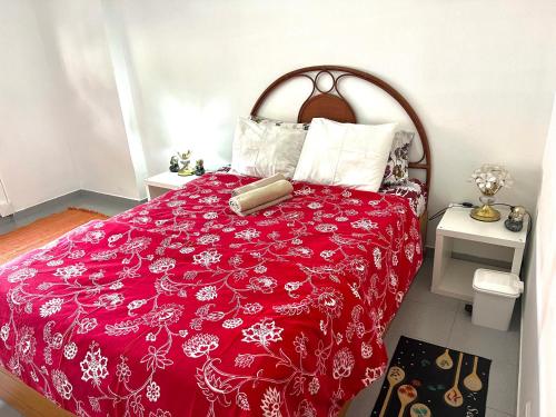 uma cama com um edredão vermelho e almofadas brancas em Charming House 2 na Amadora
