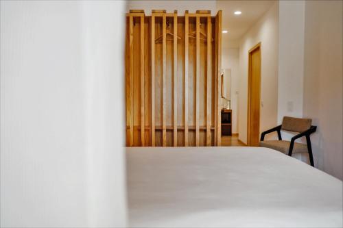 a bedroom with a white bed and a chair at Casa do Santo - Wine & Tourism in Provesende