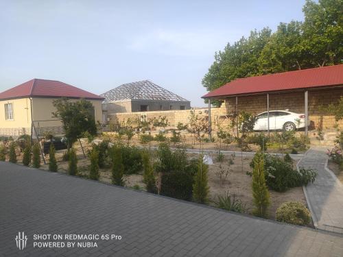 a house with a car parked in a garden at Novxani jorat beach area in Sumqayyt