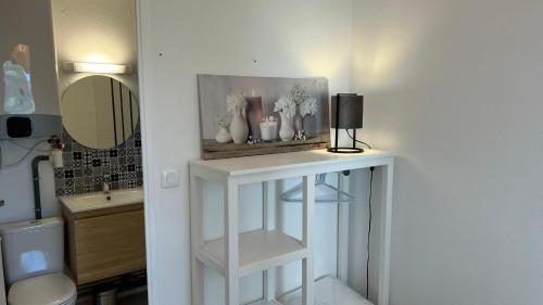 La salle de bains est pourvue d'une table blanche avec une lampe. dans l'établissement Appartement 2 pièces en rez-de-chaussée dans résidence avec accès direct à la plage, à Cabourg