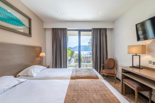 a hotel room with a bed and a desk and a window at Hotel Shegara in Porto-Vecchio