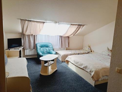 a hotel room with two beds and a blue chair at Saules rati in Daugavpils