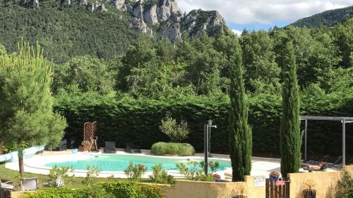 a swimming pool with trees in front of a mountain at Le Jardin des Gorges in Belvianes-et-Cavirac