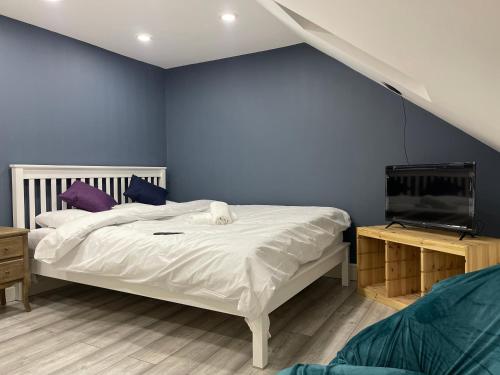 a bedroom with a white bed and a blue wall at EAST LONDON APARTMENTS SELF check in in London