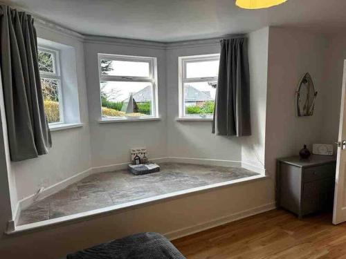 a bath tub in a room with two windows at Netherby Grange Garden Apartment with Sea Views in Llandrillo-yn-Rhôs