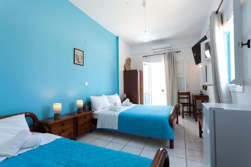 a blue room with two beds and a table at Stella's place, Vlichada in Vlychada
