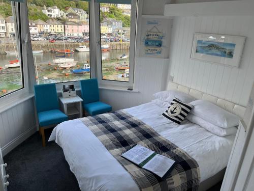 a bedroom with a bed and two blue chairs at Shellseekers Guest House in Looe