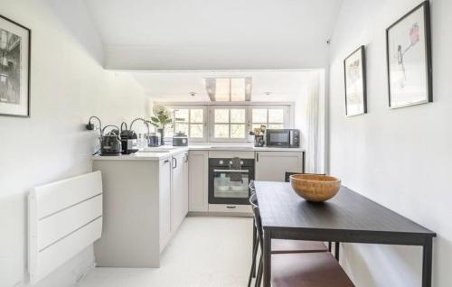 une cuisine blanche avec une table noire et une table dans l'établissement Le cocoon de Marie Astrid- Centre&plage Arcachon, à Arcachon