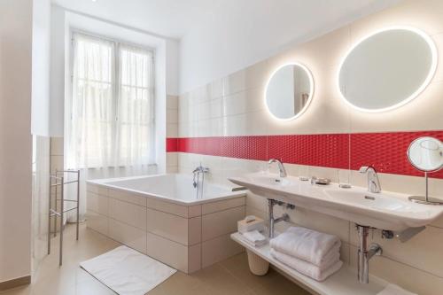 a bathroom with two sinks and a tub and two mirrors at Château de Mauvilly in Mauvilly