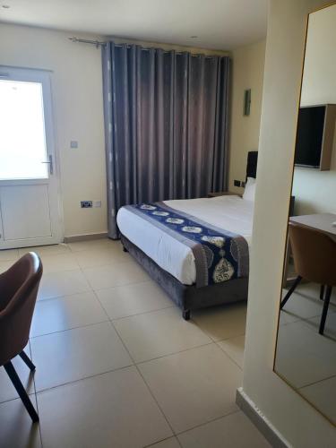 a bedroom with a bed and a desk and a mirror at Lagoonbeachhotel in Keta