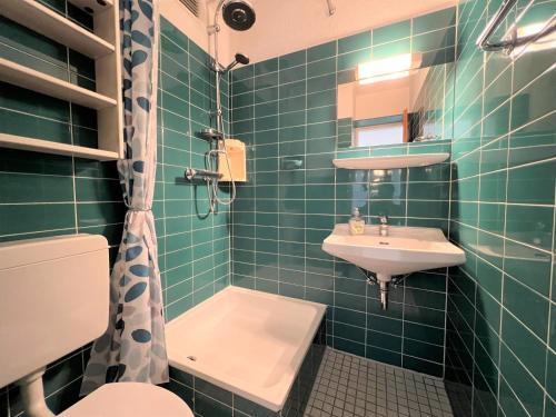 uma casa de banho com azulejos verdes, um lavatório e um WC. em Ferienpark Sierksdorf App 202 - Strandlage em Sierksdorf