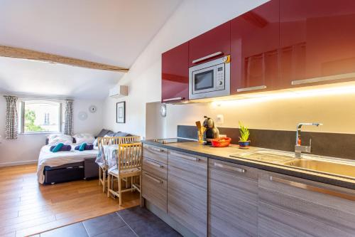 - une cuisine avec des placards rouges et un lit dans une chambre dans l'établissement 6 - Charming studio,Heart old town, beach walk, à Antibes
