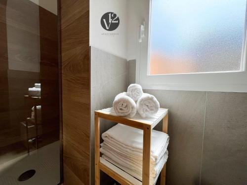 a bathroom with towels on a shelf next to a shower at V12 Apartments Puglia Modugno in Modugno