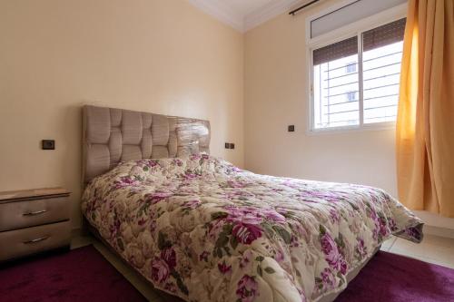1 dormitorio con 1 cama con colcha de flores y ventana en App GH7, en Agadir
