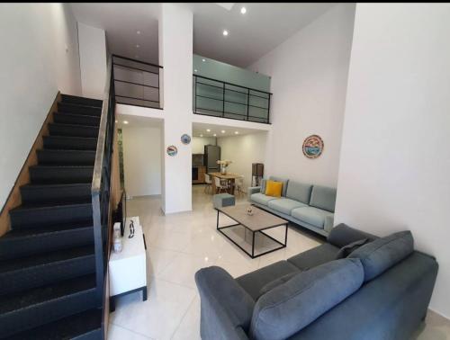 a living room with a couch and a staircase at Apartament me qera Dublex Lungomare in Vlorë