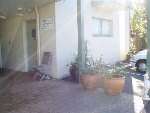 a patio with a chair and potted plants in front of a building at Fernhill Motor Lodge in Lower Hutt