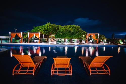 three chairs and a pool at night at Slaviero Ingleses Convention in Florianópolis