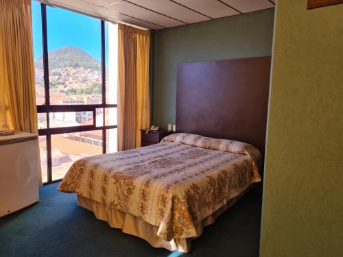 sypialnia z łóżkiem i dużym oknem w obiekcie Glorieta Hotel w mieście Sucre