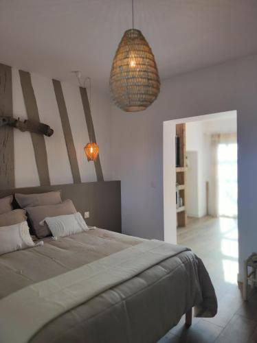 a bedroom with a large bed and two pendant lights at Le clos des crins in Pavilly