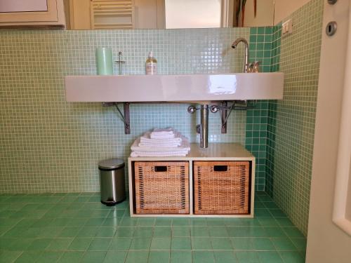 a bathroom with a sink and wicker baskets under a sink at Appartamento in Villa Mimosa in Cervo