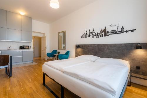 a bedroom with a large white bed and a kitchen at EA ApartHotel Melantrich in Prague