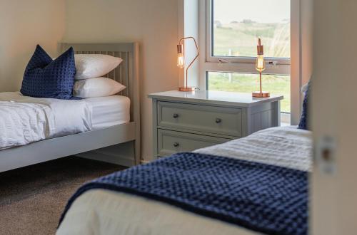 1 dormitorio con 2 camas y ventana en Coleil Cottage en Garrabost