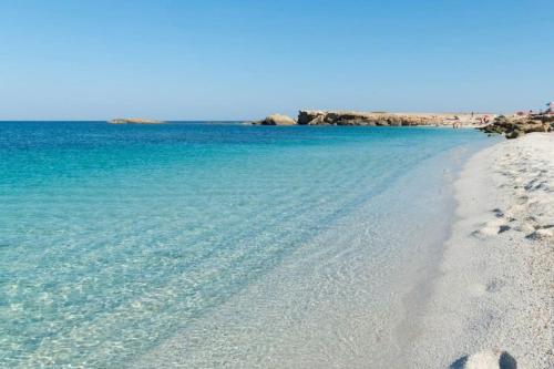 a beach with clear blue water and footprints in the sand at [Torregrande]APT.1-Con terrazzo a pochi metri dal mare - Free Wi-Fi in Torre Grande