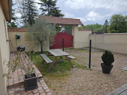 a picnic table in a yard next to a fence at L'Abaca 27 in Sainte-Geneviève-lès-Gasny