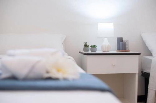 a bed with white pillows and a night stand with plants on it at [Torregrande]APT.1-Con terrazzo a pochi metri dal mare - Free Wi-Fi in Torre Grande