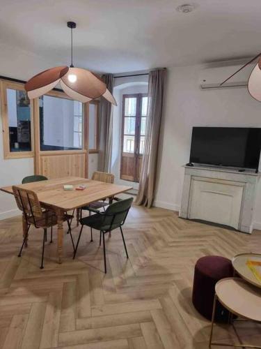 un salon avec une table, des chaises et une télévision dans l'établissement Appartement au cœur de la ville, à Corte