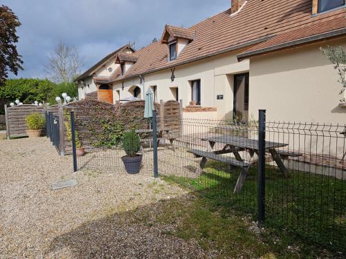 a fence with a picnic table in front of a house at L'Abaca 27 in Sainte-Geneviève-lès-Gasny